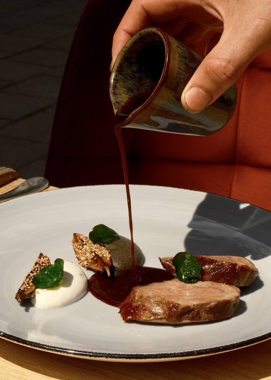 Barbecued lamb rump with jus being poured at the table